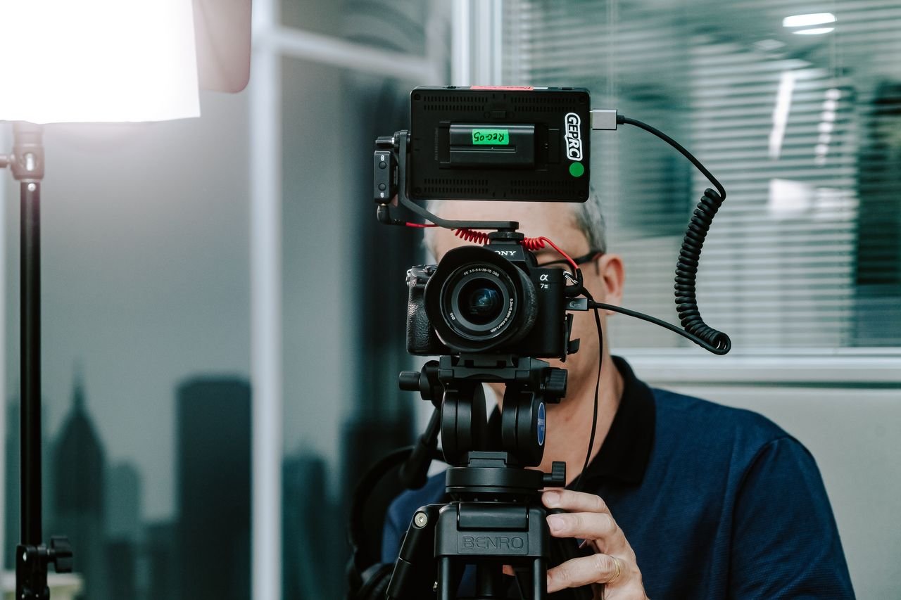 A videographer setting up a camera with additional gear in a modern studio environment.